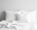 Lit blanc douillet avec oreillers et couverture dans une chambre minimaliste