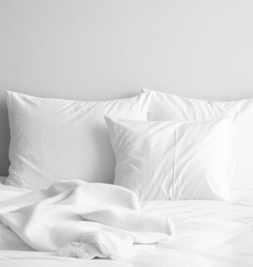Lit blanc douillet avec oreillers et couverture dans une chambre minimaliste